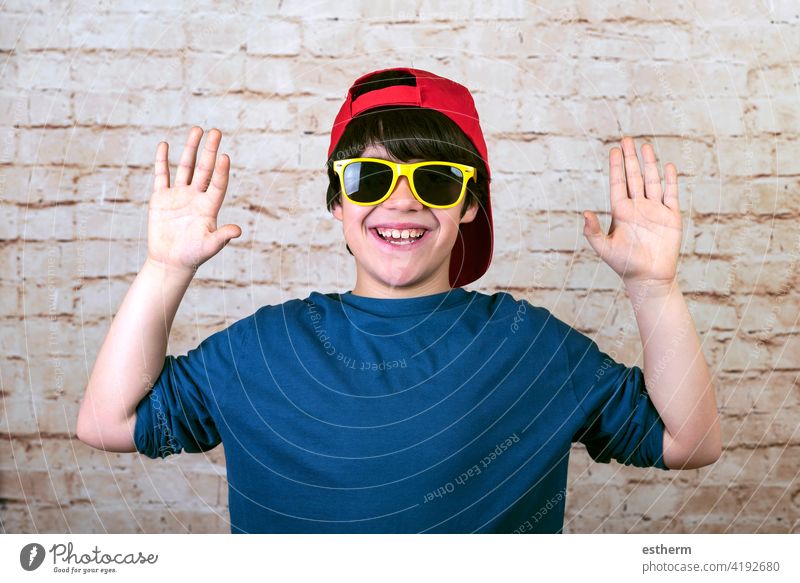 happy and smiling boy with cap and sunglasses showing palms of hands accessory kid happiness caucasian fashionable lifestyle summer childhood modern holidays