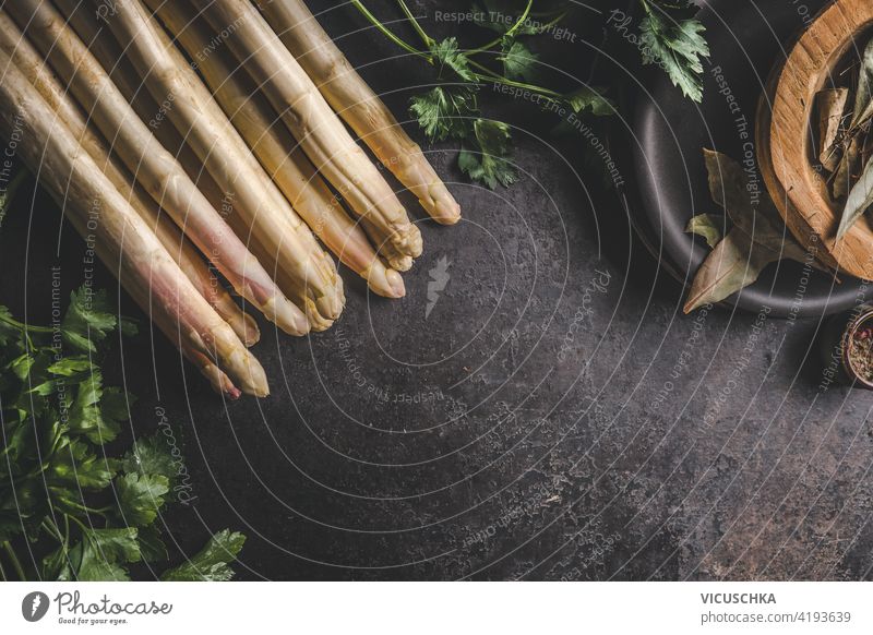 Close up of asparagus bunch on dark rustic table with fresh ingredients and kitchen utensils .Top view. close up top view above copy space healthy bundle white