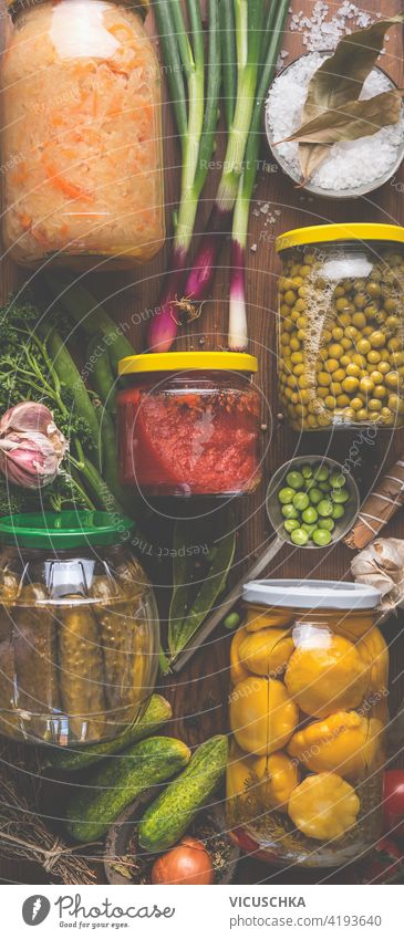 Carious pickled colorful vegetables in jars on wooden background with ingredients, herbs and spices. Copy space. Mock up. Harvest preserving. Fermented  food. Canned vegetables . Top view