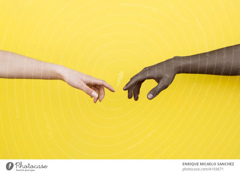 White hand and black hand about to touch on yellow background people friendship together clasped african international relationship skin unity copy space male