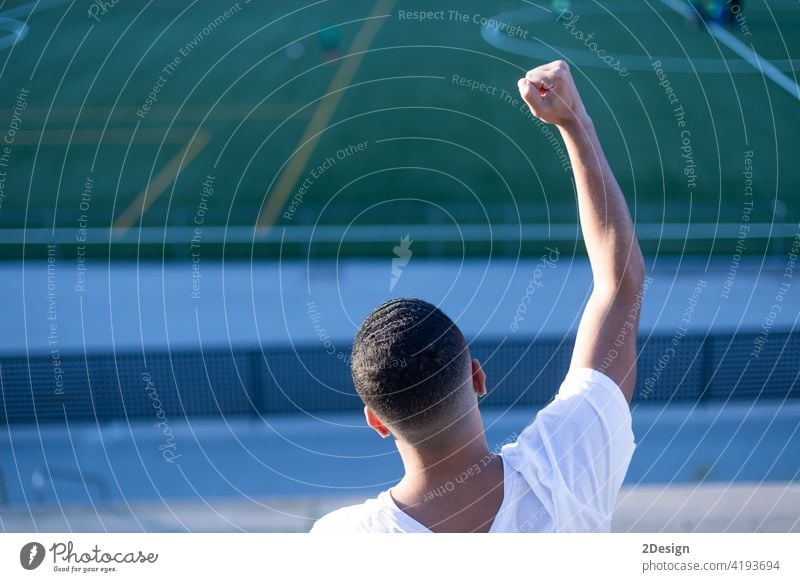 Young man celebrating victory on bleachers watching football arms raised goal winner male soccer soccer staduim black leisure audience sport success athletic