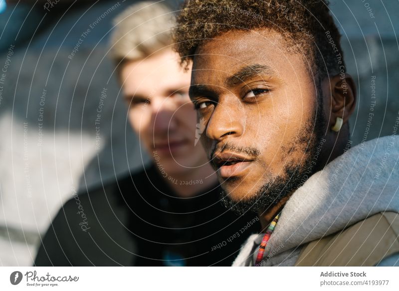 Young diverse guys standing on pavement in city district together friend street urban building exterior positive confident style optimist young multiracial