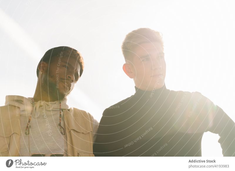 Young diverse guys standing on pavement in city district together friend street urban building exterior positive confident style optimist young multiracial