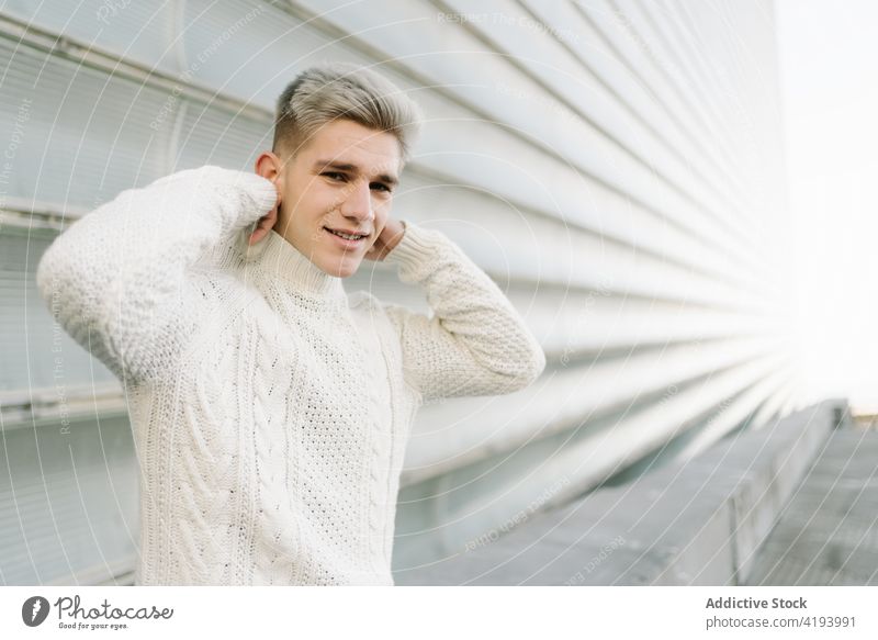 Trendy young man standing near modern buildings street city wait appointment punctual architecture downtown urban male trendy sweater wristwatch style impatient