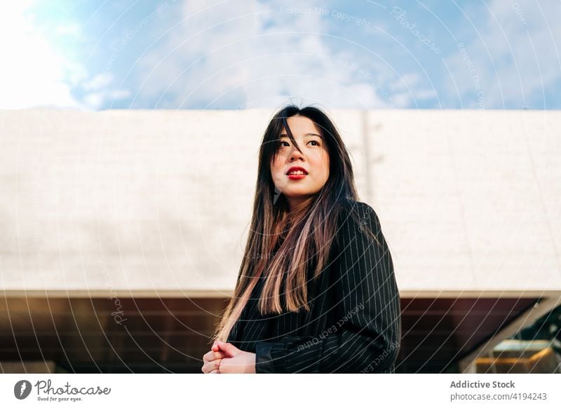 Long hair brunette asian woman standing on stairs and looking away japanese young female model chinese style attractive lady street modern stylish portrait