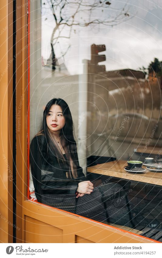 Long-haired brunette Asian woman having a coffee oh a coffee shop asian people female chinese cafe cup person drink hot long hair twenties 20s table together