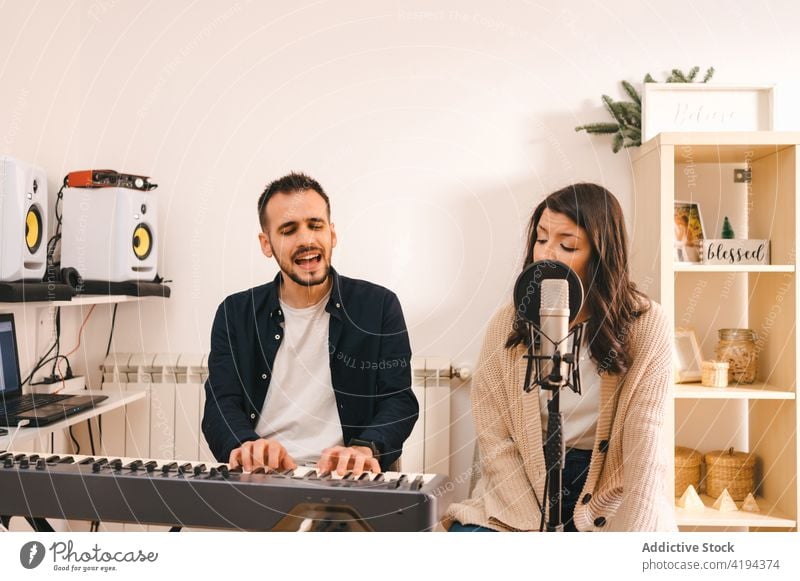 Couple recording song at home couple sing play synthesizer music musician together singer microphone sound audio rehearsal melody rhythm instrument perform