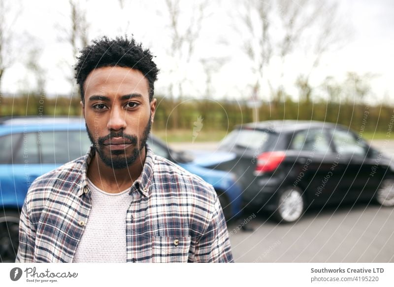 Portrait Of Uninsured Male Driver At Fault After Road Traffic Accident man driver car accident wreck crash portrait looking at camera uninsured fault blame