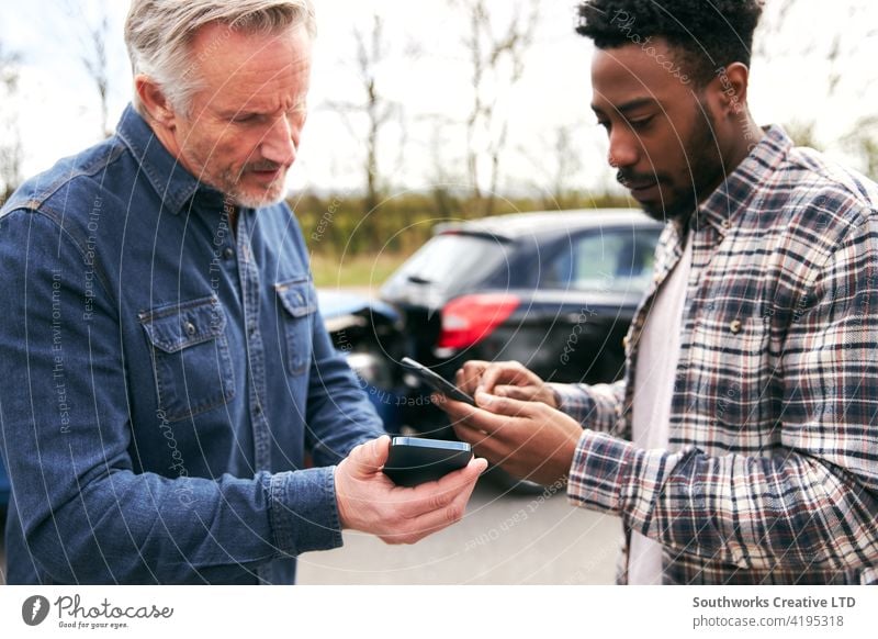 Senior Male Driver Exchanges Car Insurance Details With Younger Motorist After Road Traffic Accident men man driver car accident wreck crash insurance claim