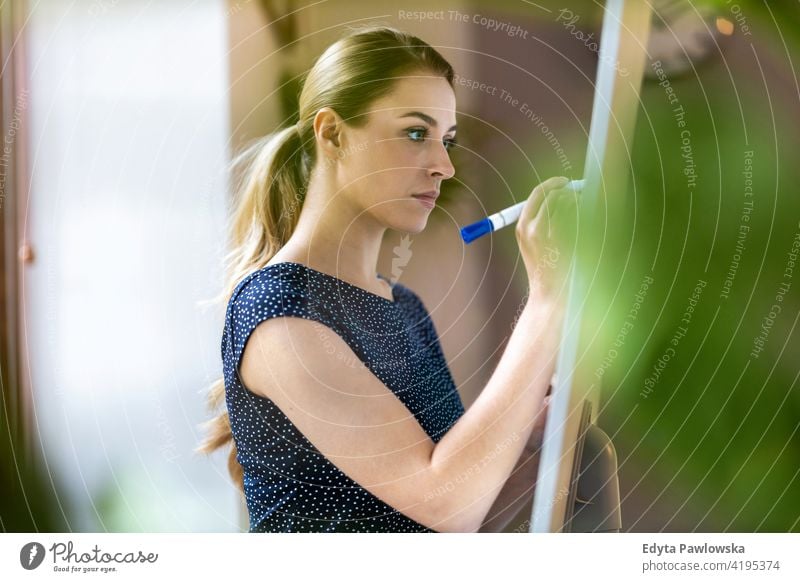 Young businesswoman writing on white board with her marker pen in office girl people Entrepreneur successful professional young adult female lifestyle indoors