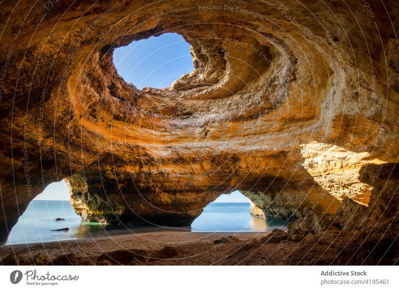 Grotto on coast against sea under blue sky cave highland nature landscape geology majestic hole horizon grotto lagoa town ocean sandy rough cavern endless beach