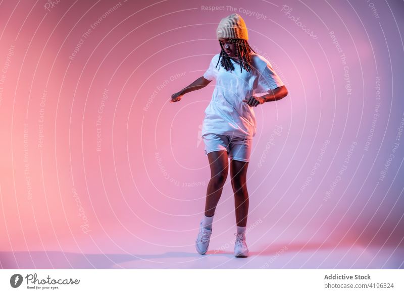 Black teenage girl dancing freestyle in studio dancer hobby cool hip hop move motion energy neon light dynamic studio shot generation perform urban active braid