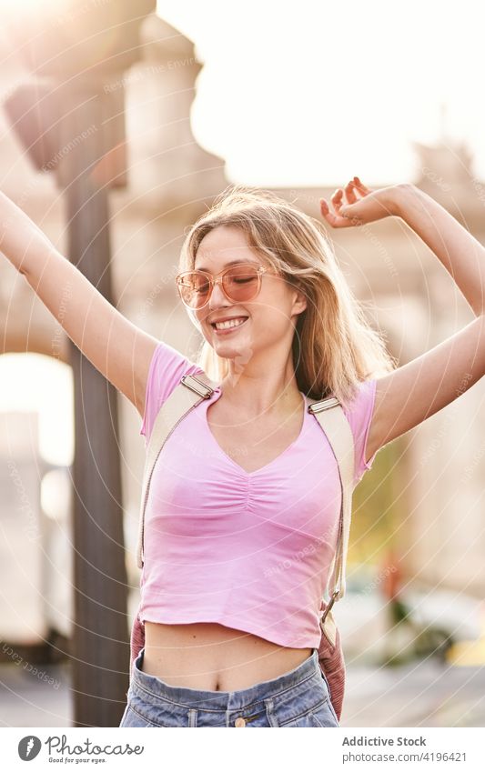 Joyful young woman enjoying vacation on city street happy teenage holiday travel fun carefree pleasure female cheerful sunshine arms raised optimist