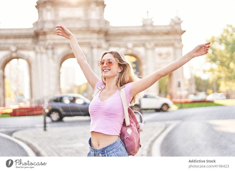 Joyful young woman enjoying vacation on city street happy teenage holiday travel fun carefree pleasure female cheerful sunshine arms raised optimist