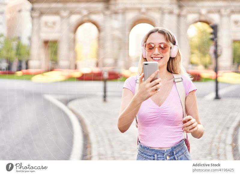 Delighted teen woman taking selfie on smartphone teenage cheerful using music headphones listen sightseeing female device self portrait sunglasses optimist