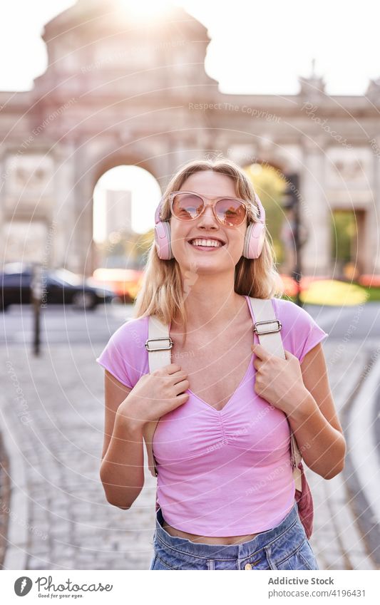 Joyful young woman enjoying vacation on city street happy teenage headphones holiday travel fun carefree pleasure cheerful sunshine optimist lifestyle smile