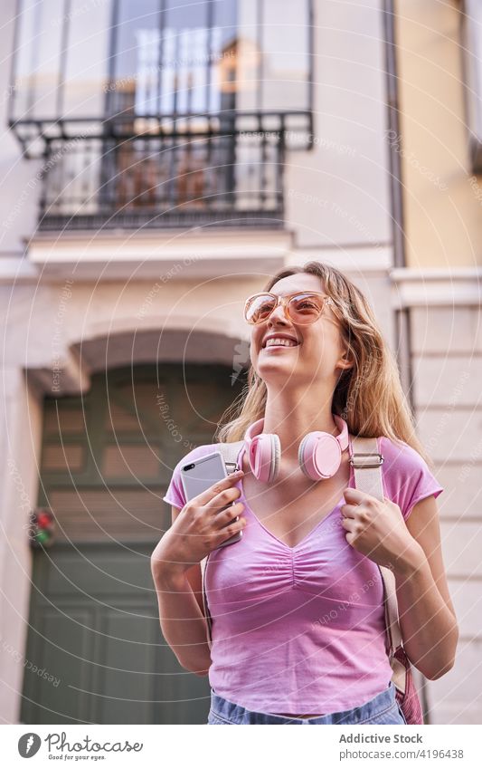 Joyful young woman enjoying vacation on city street happy teenage headphones holiday travel fun carefree pleasure cheerful optimist lifestyle smile trip stand