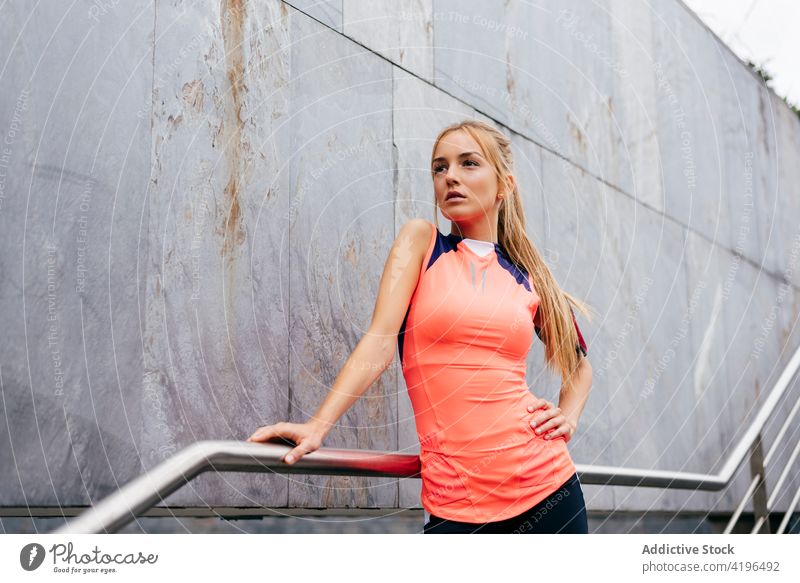 Attractive blonde sportswoman resting on stairs girl street city run running exercise colorful building attractive sportswear athlete female caucasian fit