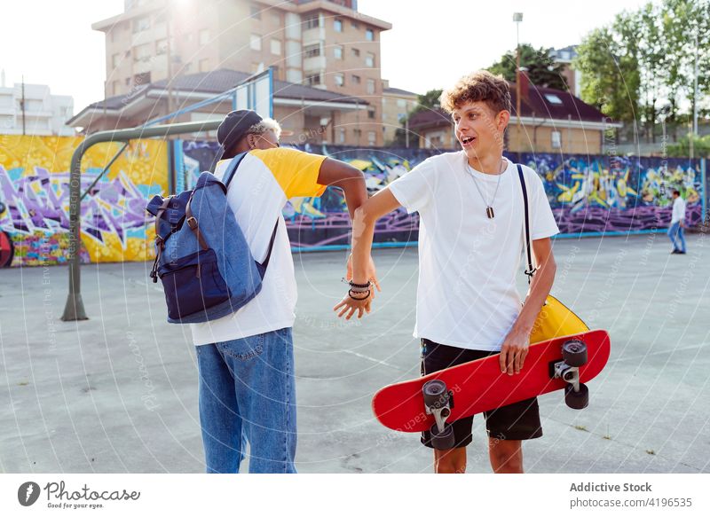 Two teenage boys shaking hands and laughing on the street autumn backpack black caucasian cheerful city colorful companionship daylight ethnic fellowship