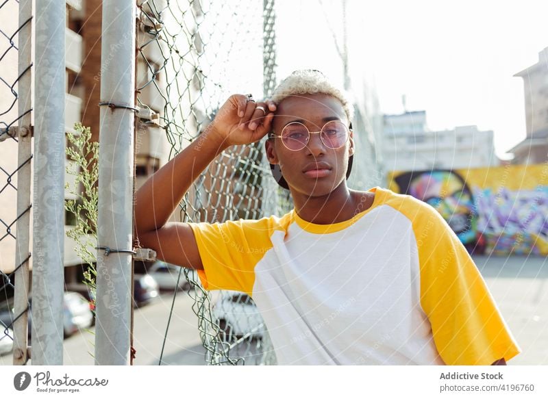 Handsome young black man lying on a fence on the street attractive boy cap cheerful city colorful confident daylight ethnic handsome horizontal laying leisure