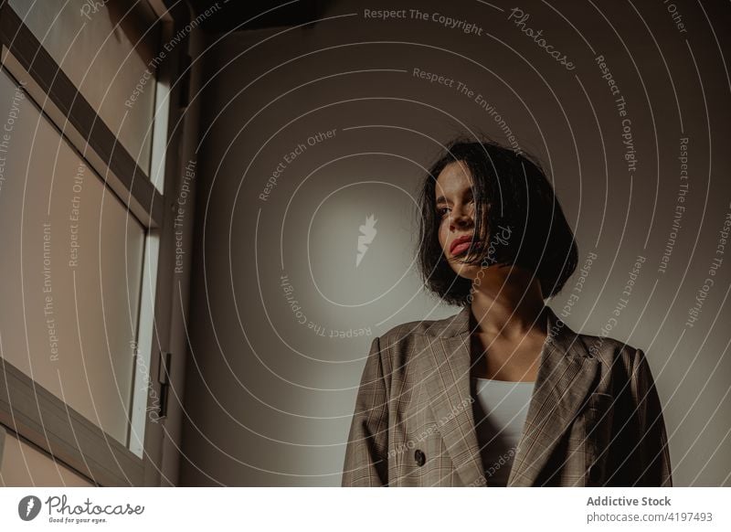 Stylish woman standing in room near window style outfit determine brutal trendy confident self assured female hat jacket appearance personality fashion serious