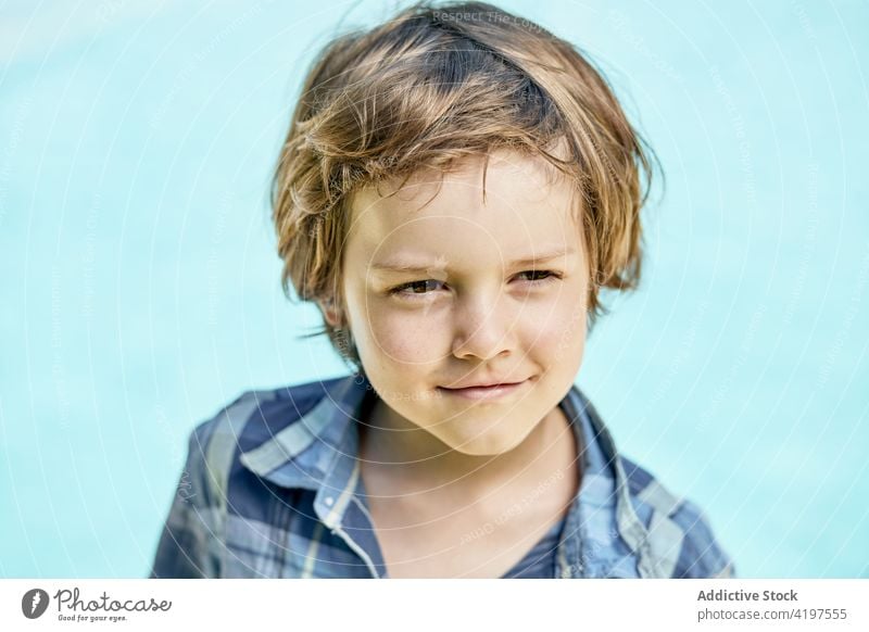 Happy cute child smiling and looking at camera in sunlight smile happy portrait style content holiday positive childhood glad trendy kid boy checkered shirt