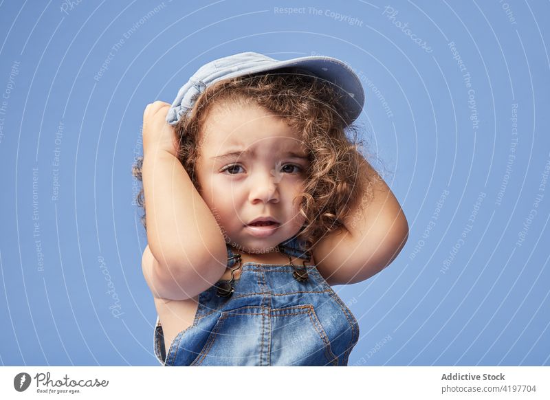 Cute little girl in hat and denim outfit kid portrait cute personality childhood adorable charming gaze headgear headwear brown eyes curious studio shot small