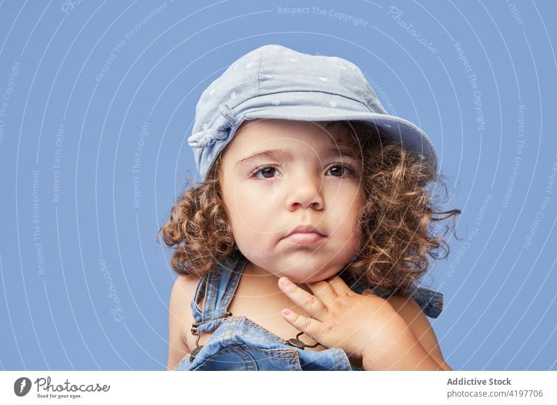 Cute little girl in hat and denim outfit kid portrait cute personality childhood adorable charming gaze headgear headwear brown eyes curious studio shot small