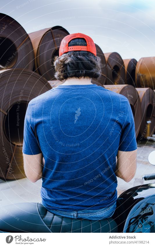 Anonymous man standing near steel rolled coils in industrial area metal factory alone style storage stack manufacture industry material male young dark hair