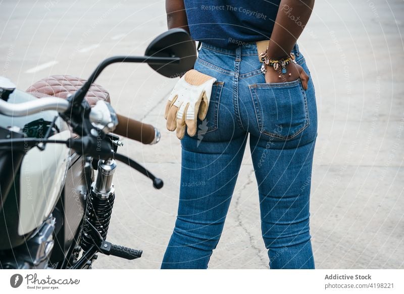 Anonymous black woman standing on sea promenade near motorbike style alone admire biker seafront rest motorcycle journey vacation female young african american