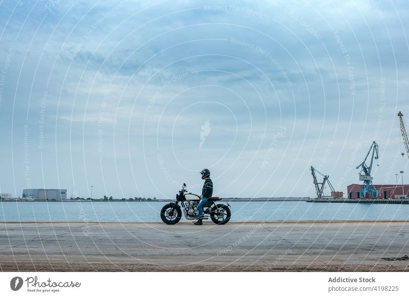 Anonymous guy sitting on motorbike and admiring sea man motorcycle embankment relax style cool construction biker recreation admire seaside male young casual