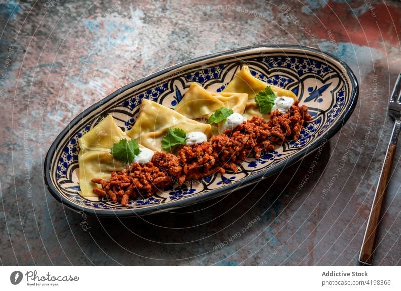 Delicious dish of dumplings with onions and minced meat aushak portion national sauce greens cuisine appetizing afghan culture beef nutrition tasty lunch plate