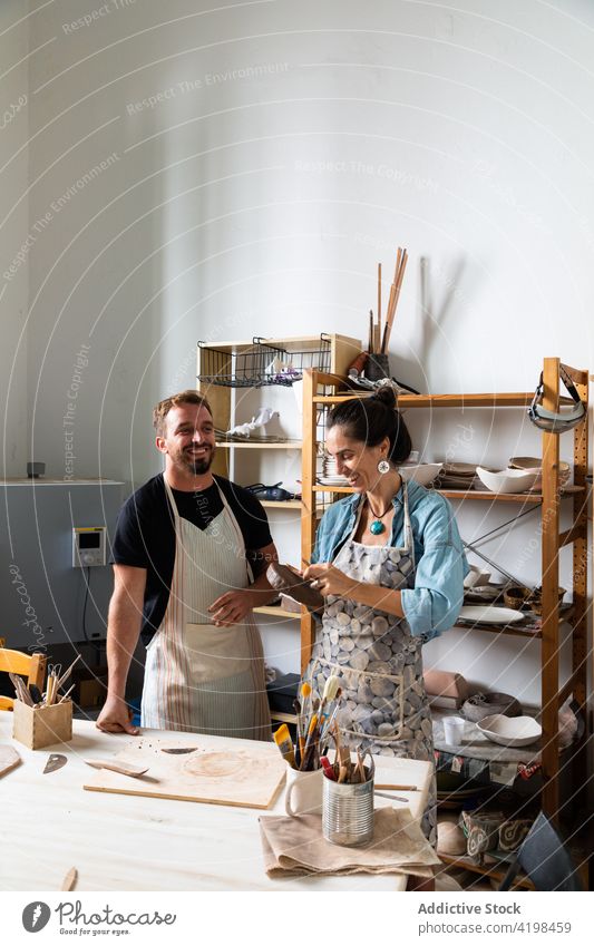 Happy coworkers sculpting clay plate in workshop colleague create clayware smile positive class hobby together skill help man woman middle age young diverse