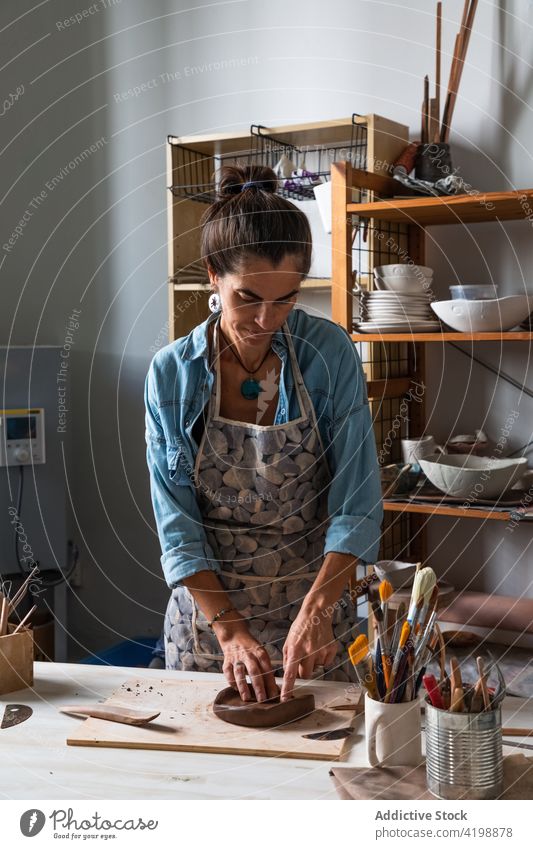 Focused craftswoman forming clay during work in art studio artisan workshop create shape concentrate talent focus skill pottery female middle age ethnic