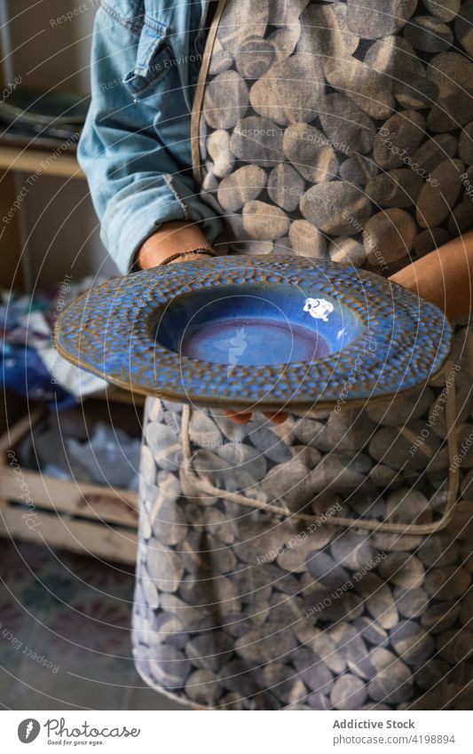 Faceless potter showing clay plate in traditional studio person demonstrate ceramic clayware artisan handmade craft skill job professional small business master