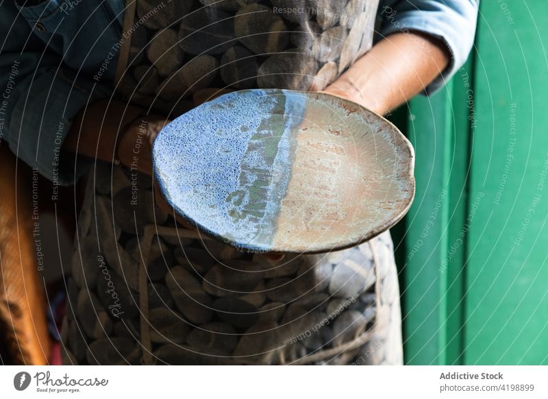 Faceless potter showing clay plate in traditional studio person demonstrate ceramic clayware artisan handmade craft skill job professional small business master