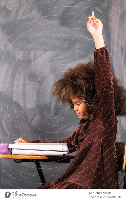 Black girl with raised hand in classroom during lesson pupil hand raised school arm raised schoolgirl study clever education ethnic african american black