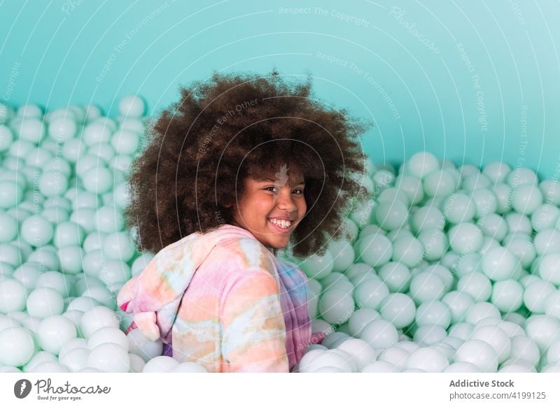 Cheerful child in ball pit play cheerful pool plastic happy afro hairstyle ethnic black african american kid fun childhood having fun enjoy content glad cute