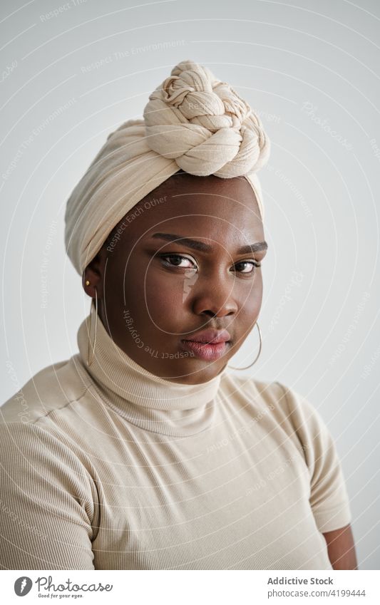 Confident young black lady in turban looking at camera woman style confident gorgeous model portrait appearance vogue personality feminine self assured chic