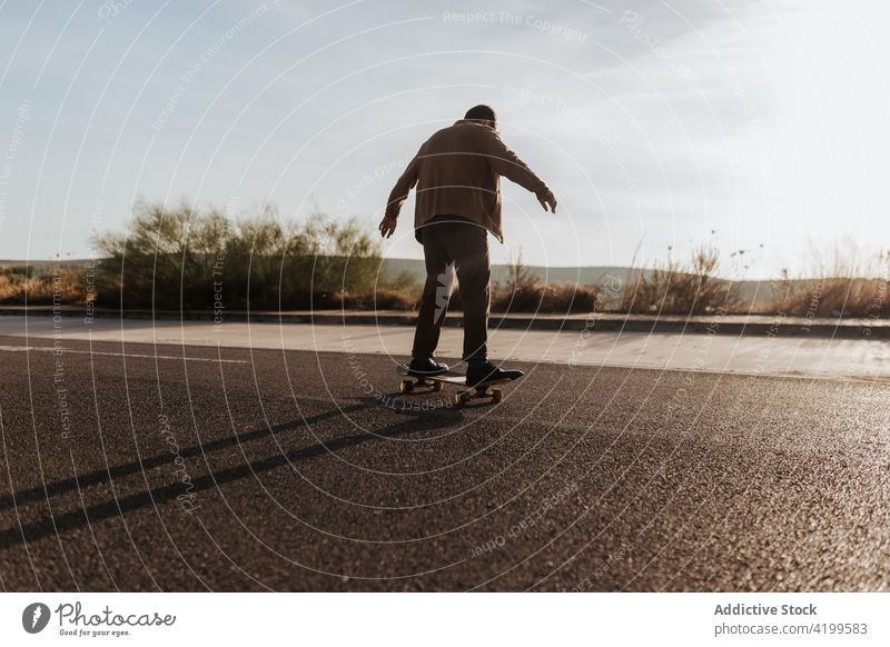 Unrecognizable skater on asphalt road man ride skateboard countryside rural nature hobby subculture practice skill male energy cool motion sport balance move