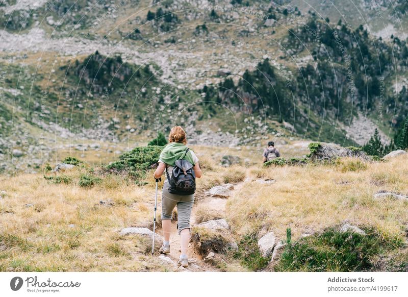 Unrecognizable couple of hikers trekking on mountains landscapes stroll path vacation route nature trip pole summer together partner rough pathway travel