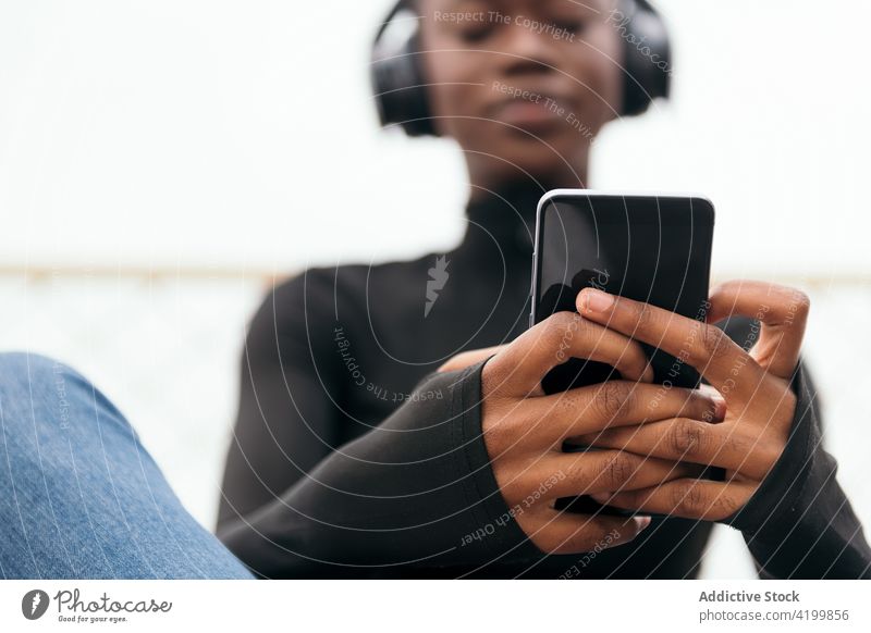 Smiling black woman in headset watching smartphone on street african american song listen short hair content internet portrait using gadget town device browsing