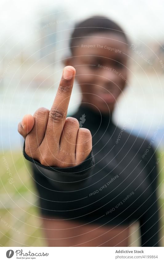 Rude black woman showing middle finger in city fuck rude rebel aggressive offensive bad gesture town outstretch smile content glad wear casual african american