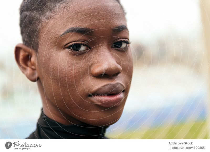 Gentle black woman in casual wear in city park feminine gentle short hair tender sincere friendly charming pleasant portrait urban lawn body belly harmony style