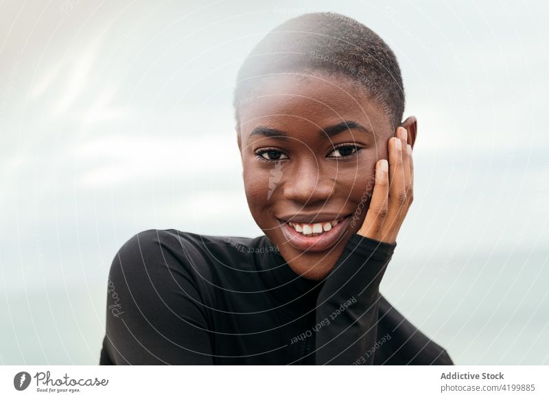 Dreamy black woman touching cheek under cloudy sky touch face dreamy short hair smile enjoy feminine gentle romantic portrait reflective mindful tender sincere