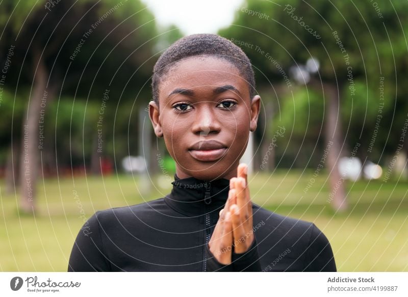 Gentle black woman in casual wear in city park feminine gentle short hair tender sincere friendly charming pleasant portrait urban lawn body belly harmony style