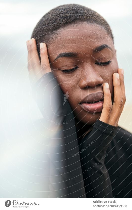 Dreamy black woman touching cheek under cloudy sky touch face dreamy eyes closed short hair smile enjoy feminine gentle romantic portrait reflective mindful