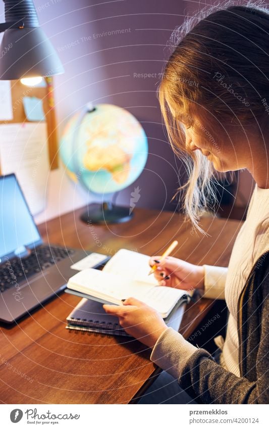 Student learning remotely from home. Young woman having classes online, making notes, reading and learning sitting at desk education indoor student working