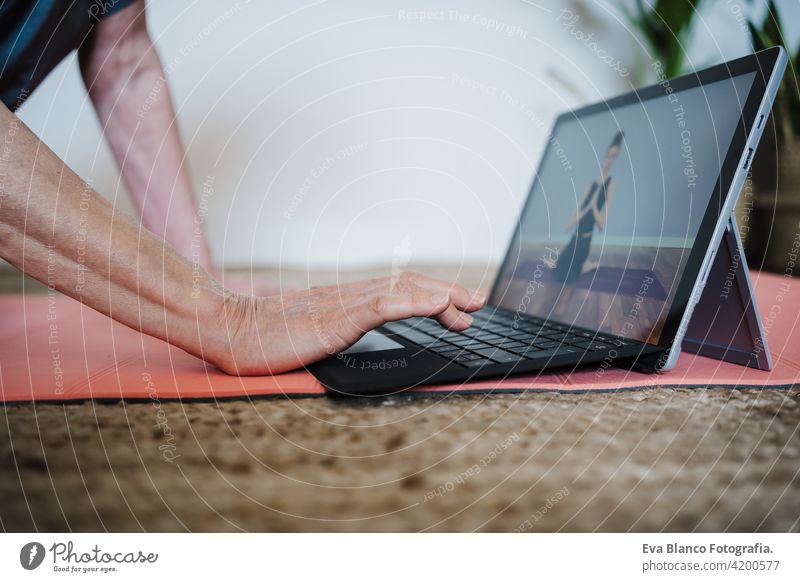 close up view of mature caucasian senior woman practicing yoga pose at home. using laptop for online class with teacher. Healthy and technology lifestyle sport