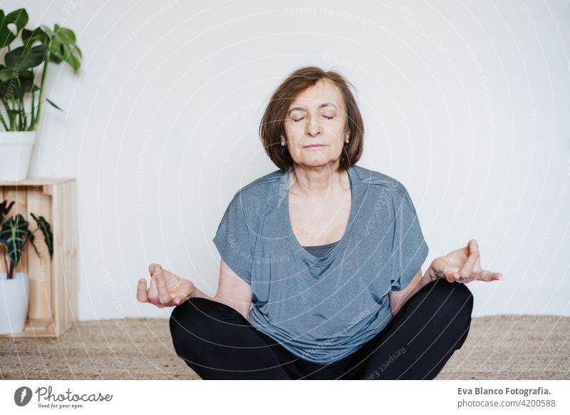 mature caucasian senior woman practicing yoga at home on yoga mat. Healthy lifestyle sport healthy floor old active pensioner gym elderly female exercise age